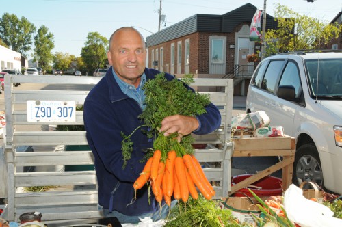 A man proudly displaying his locally grown produce at the farmers market